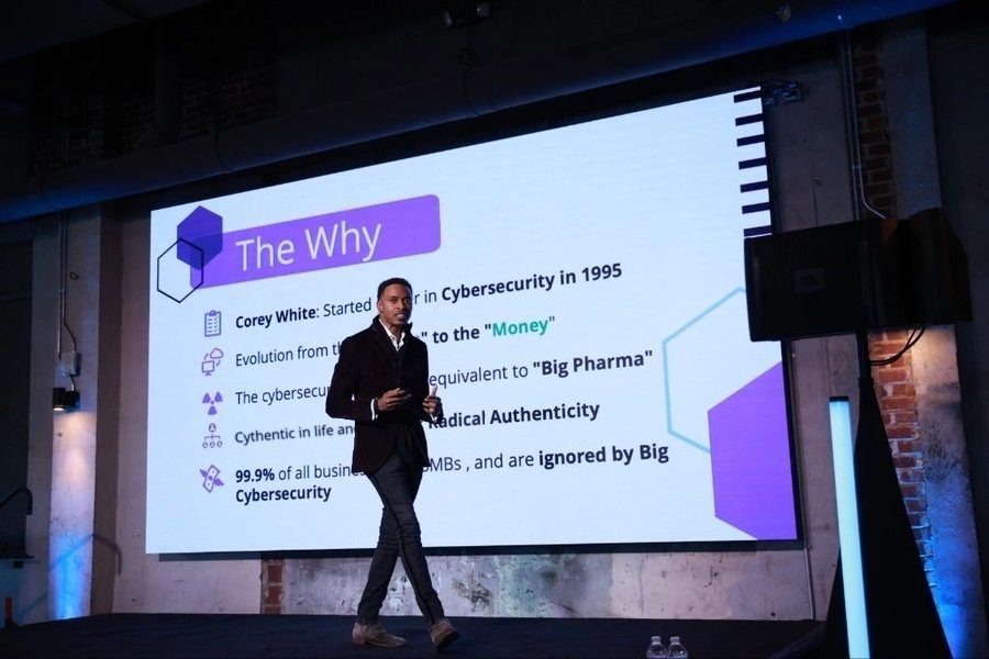 Corey White on stage presenting The Why, the Cythentic story